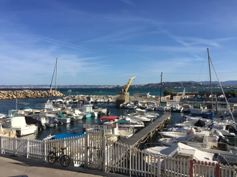 Vue du port de la Madrague avec des bateaux amarrés et un ciel ensoleillé