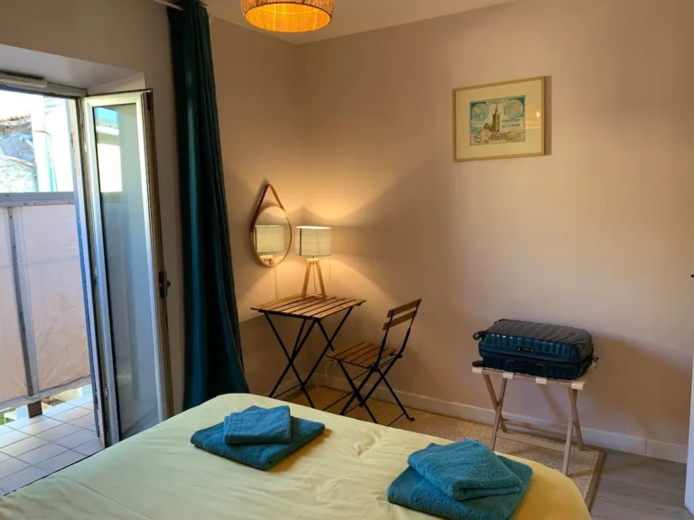Chambre lumineuse d'un T2 climatisé à Marseille, avec lit double et petite table.