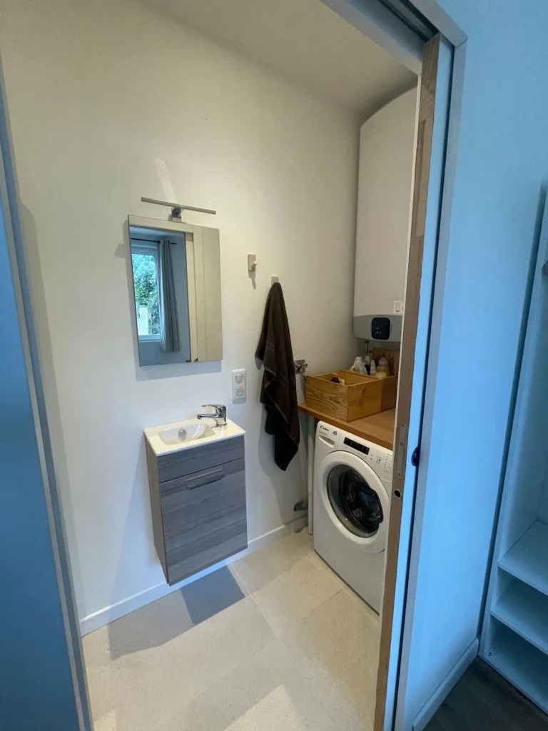 Salle de bain moderne avec machine à laver et meuble sous lavabo dans un studio à Bordeaux