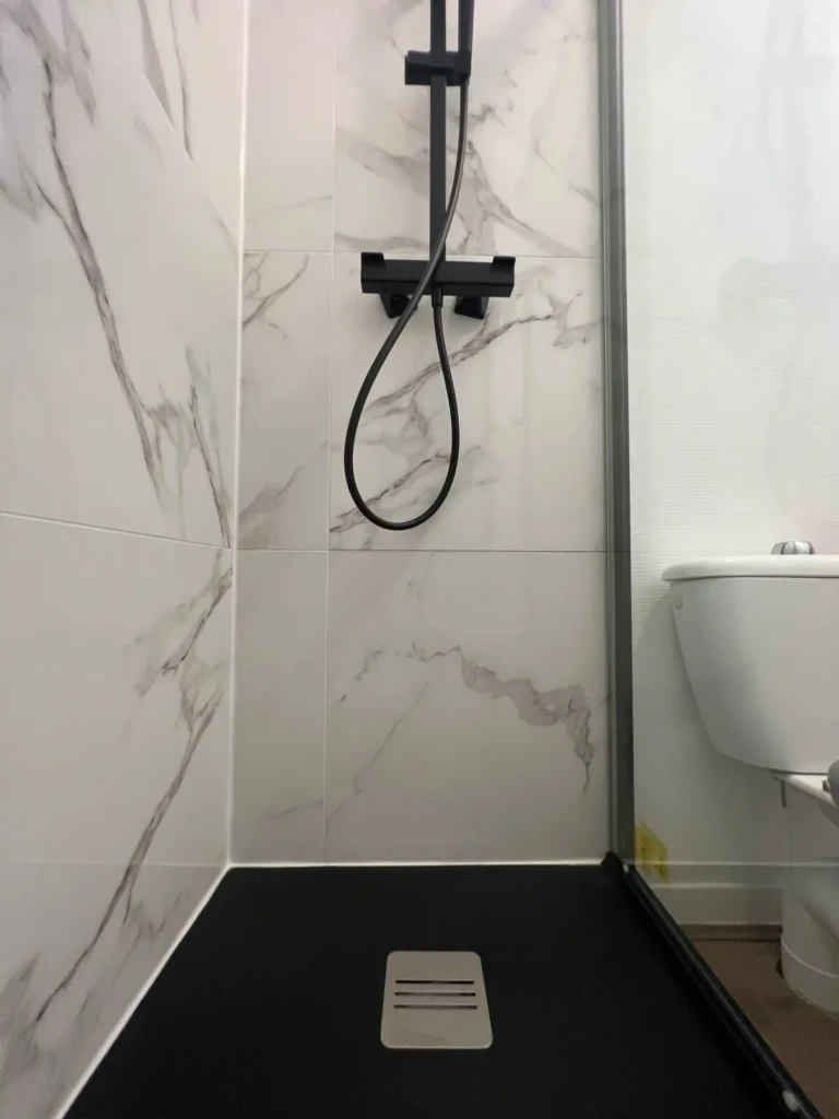 Douche moderne avec carrelage en marbre et sol noir dans un appartement à Toulouse