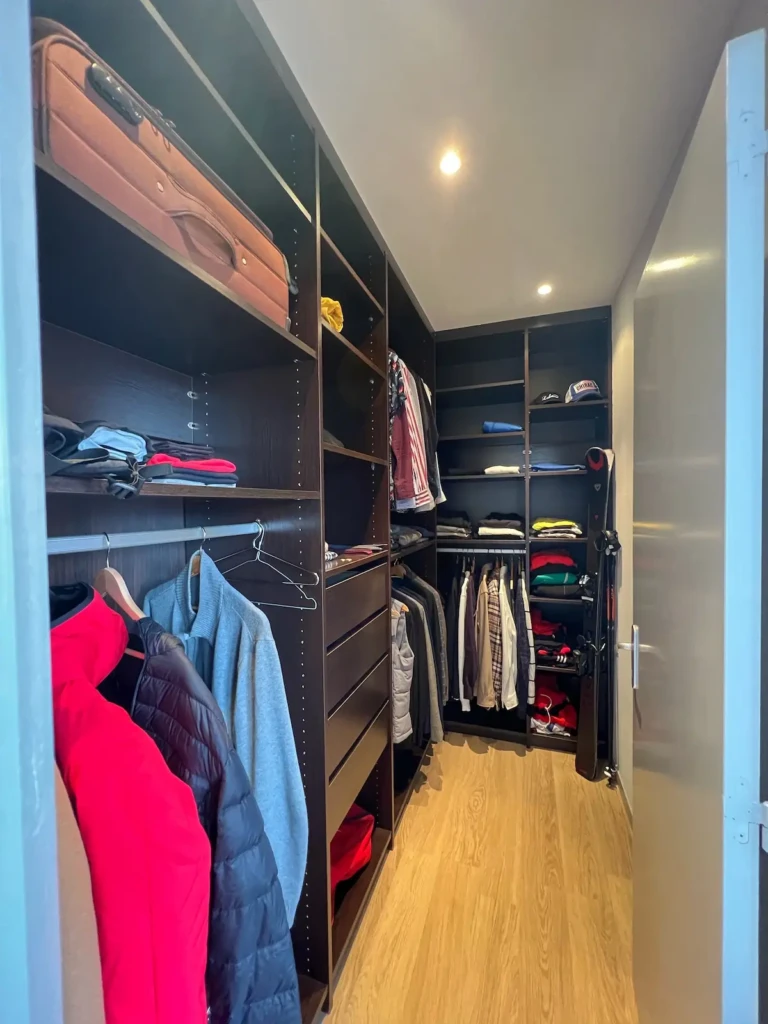 Intérieur d'un dressing spacieux avec des vêtements et une valise.