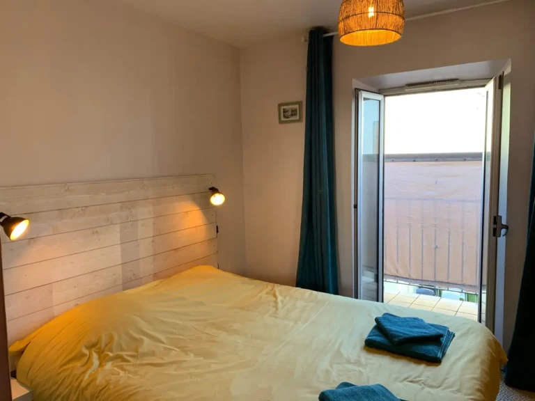 Chambre lumineuse avec lit double et accès au balcon dans un T2 au coeur de Marseille