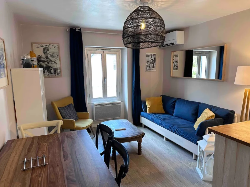 Salon lumineux d'un charmant T2 climatisé à Marseille, avec canapé confortable et table à manger.