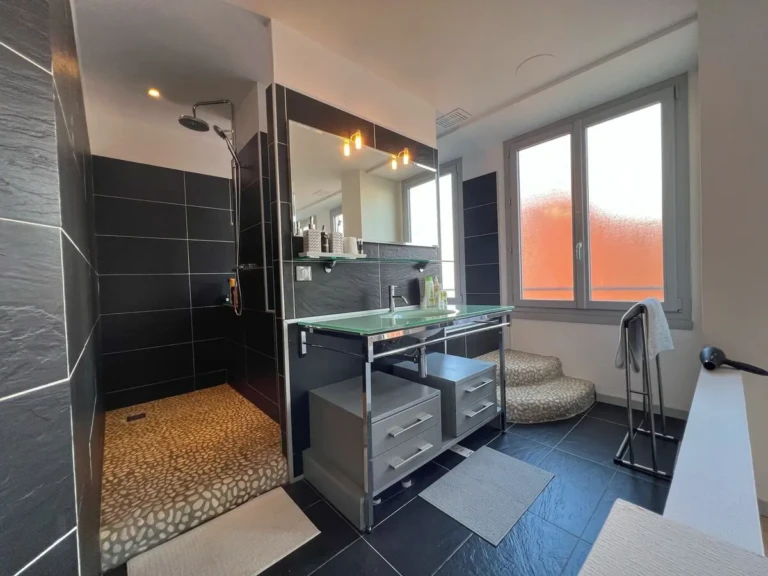 Salle de bain moderne avec douche à l'italienne et vue sur la ville.
