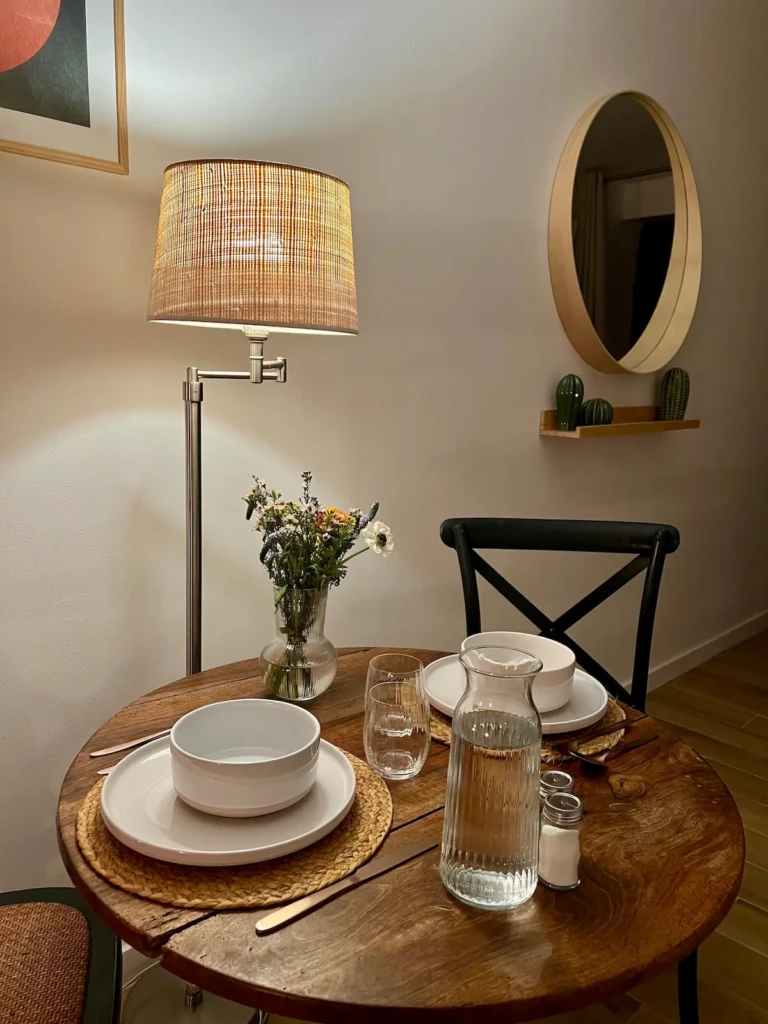 Table à manger élégante avec vaisselle, carafe d'eau et fleurs dans un studio indépendant à Bordeaux Saint Michel