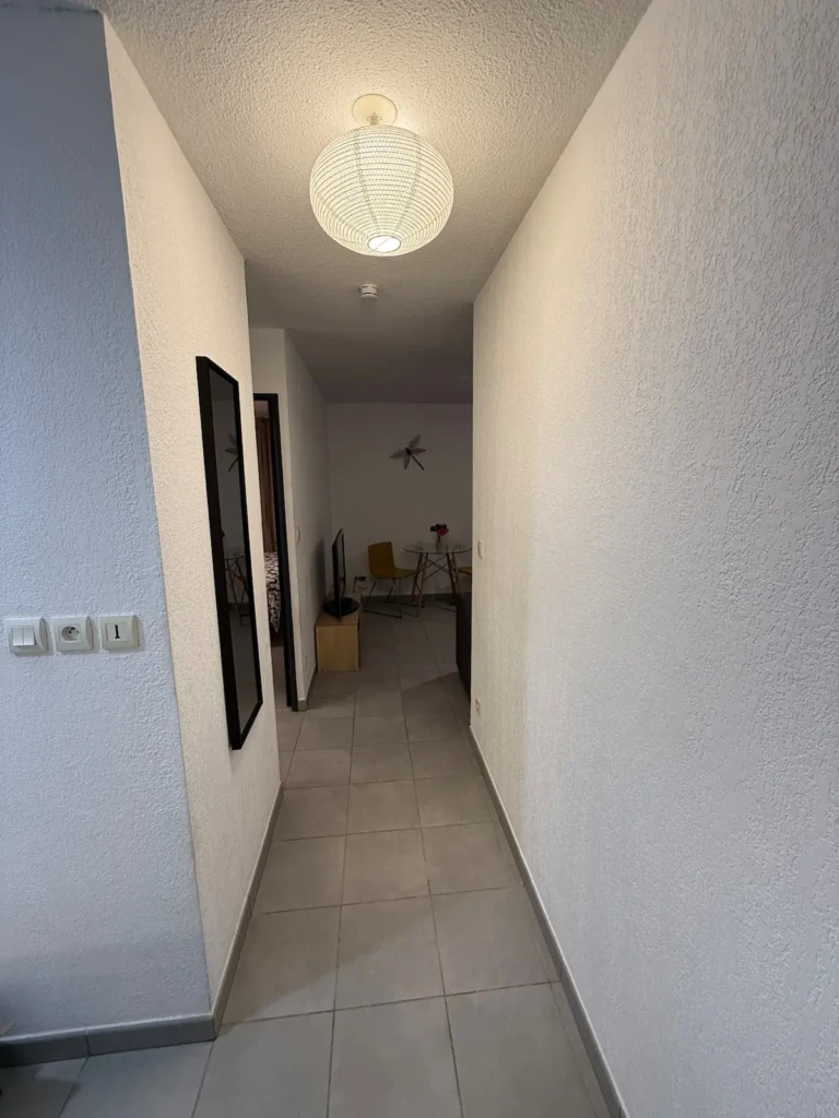 Alt:** Couloir lumineux de l'appartement moderne à Marseille, avec lampadaire design.