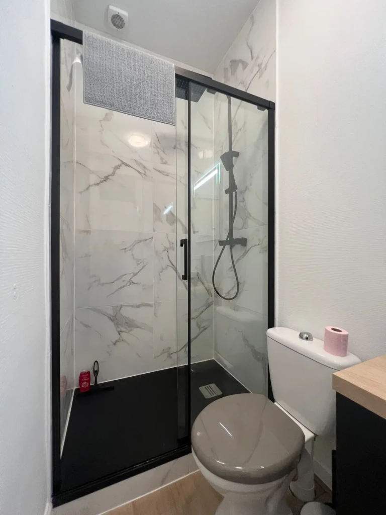 Salle de bain moderne avec douche vitrée et toilettes