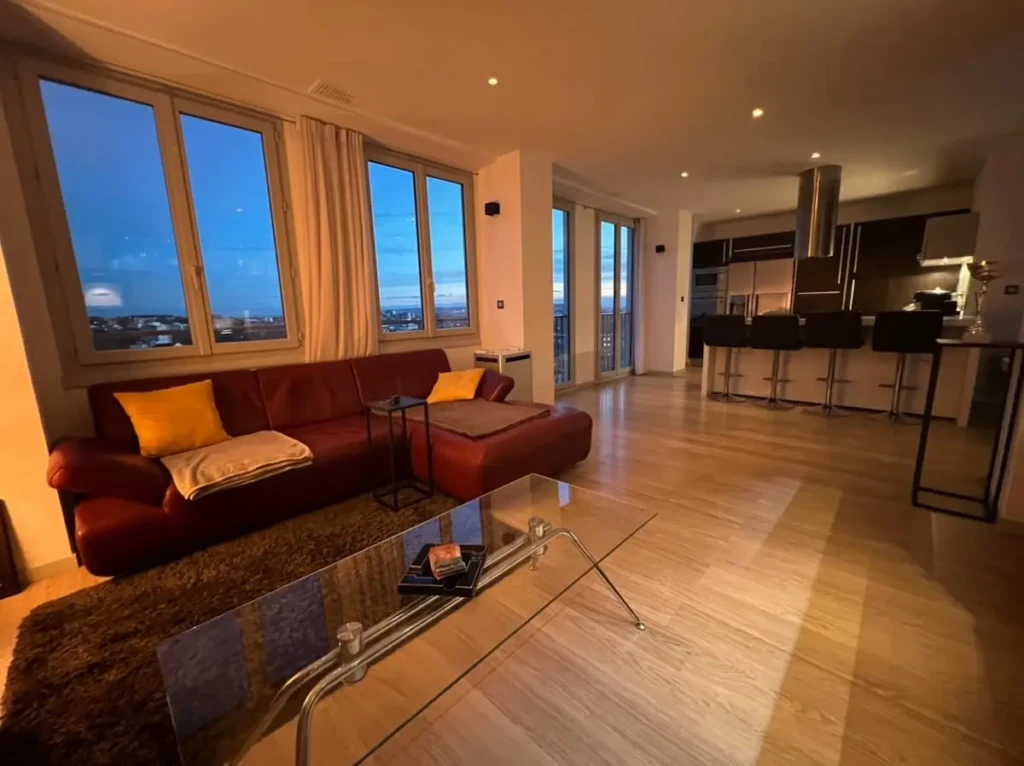 Grand séjour lumineux du penthouse avec sofa et vue sur Toulouse