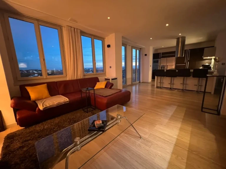 Grand séjour lumineux du penthouse avec sofa et vue sur Toulouse